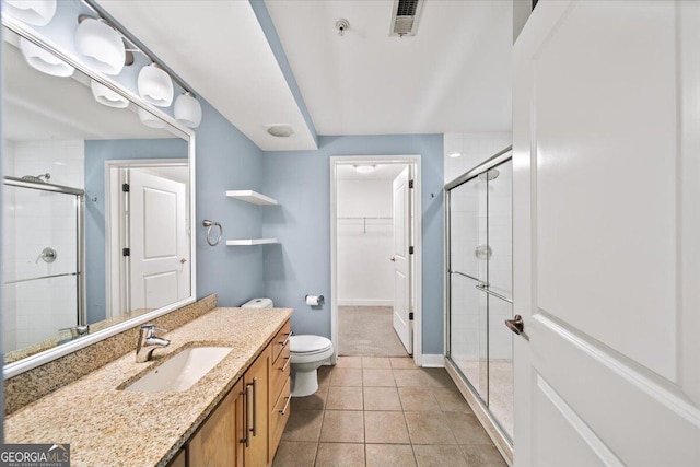 bathroom featuring a stall shower, a walk in closet, and vanity