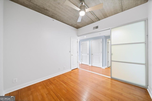 unfurnished bedroom with light wood-type flooring, baseboards, visible vents, and a ceiling fan