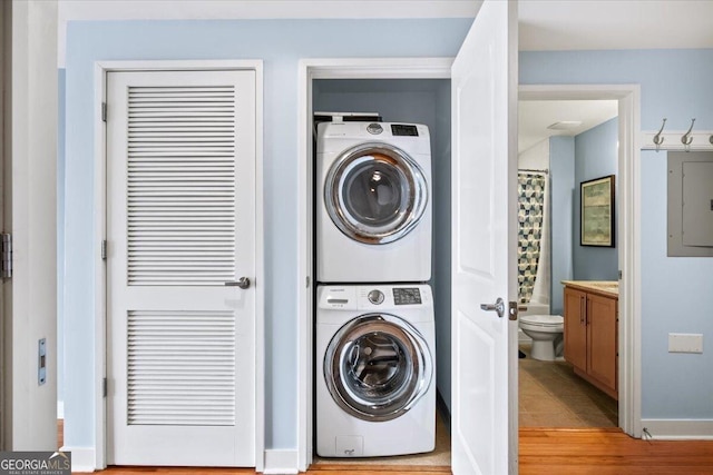 clothes washing area featuring stacked washer / dryer and laundry area