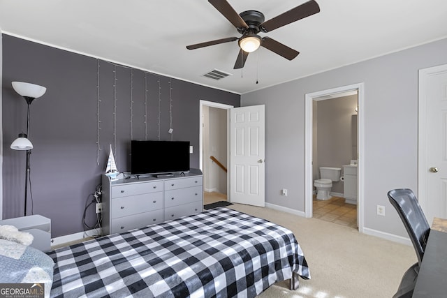 bedroom with ensuite bathroom, light carpet, and ceiling fan