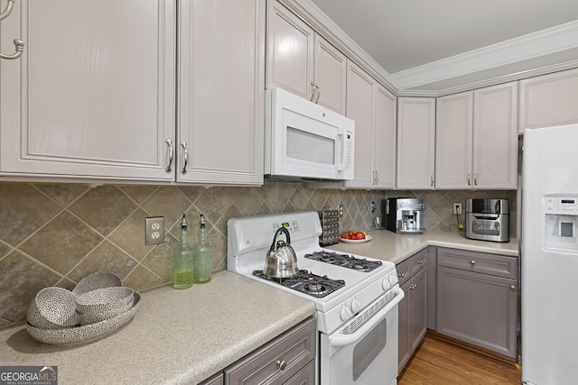 kitchen featuring light hardwood / wood-style flooring, ornamental molding, gray cabinets, white appliances, and decorative backsplash