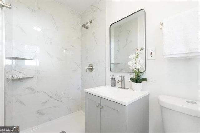 bathroom featuring vanity, toilet, and a tile shower