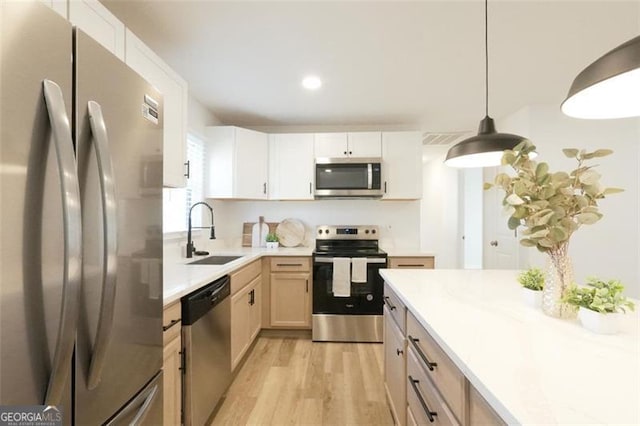 kitchen with pendant lighting, sink, appliances with stainless steel finishes, white cabinets, and light brown cabinets