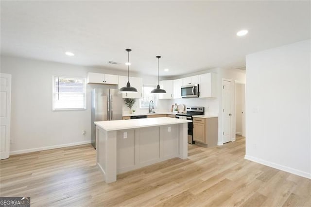 kitchen with a kitchen island, decorative light fixtures, white cabinetry, sink, and stainless steel appliances