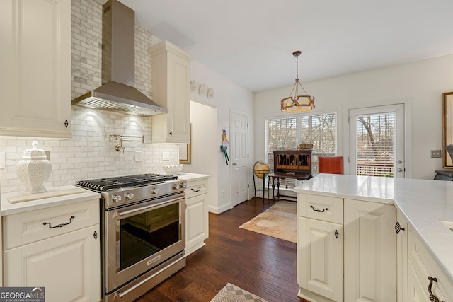 kitchen featuring dark hardwood / wood-style floors, pendant lighting, tasteful backsplash, gas stove, and wall chimney range hood