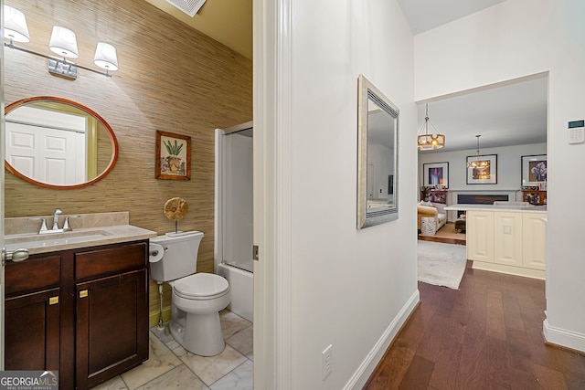 full bathroom featuring vanity, toilet, wooden walls, and bath / shower combo with glass door