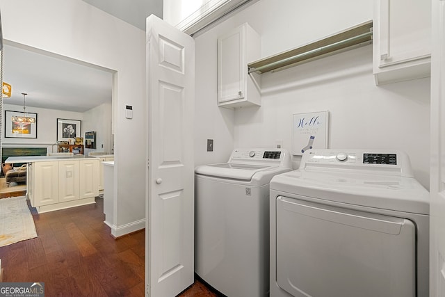 clothes washing area with washer and dryer, dark hardwood / wood-style flooring, and cabinets