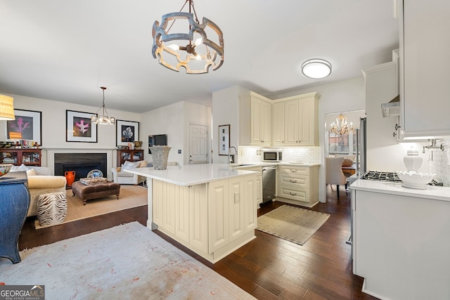 kitchen featuring a breakfast bar, appliances with stainless steel finishes, an inviting chandelier, hanging light fixtures, and decorative backsplash