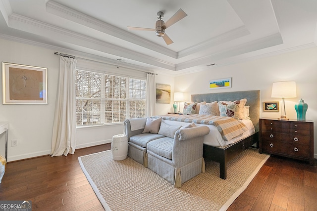 bedroom featuring ornamental molding, dark hardwood / wood-style floors, ceiling fan, and a tray ceiling