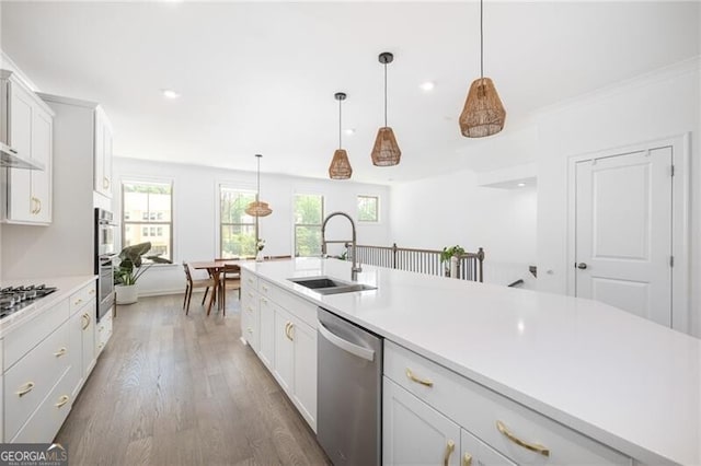 kitchen featuring dark wood-type flooring, sink, decorative light fixtures, stainless steel appliances, and white cabinets