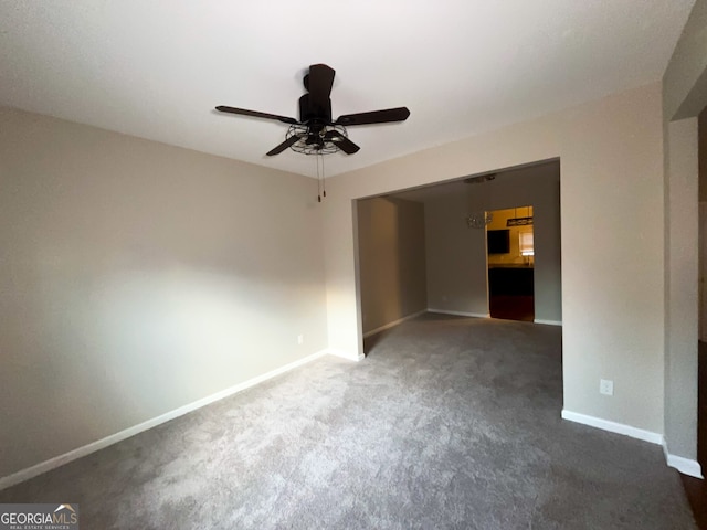 empty room featuring dark carpet and ceiling fan