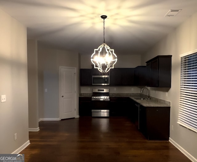 kitchen with pendant lighting, sink, appliances with stainless steel finishes, an inviting chandelier, and dark hardwood / wood-style floors