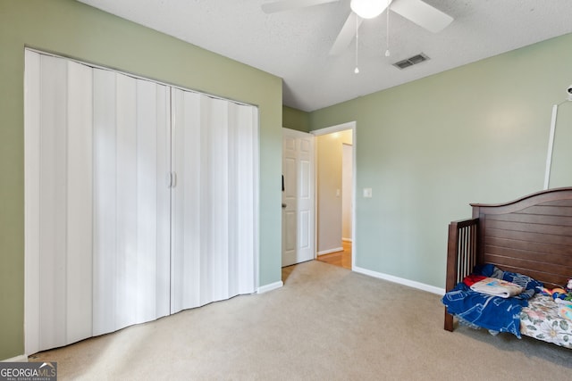 unfurnished bedroom with light carpet, a textured ceiling, and ceiling fan