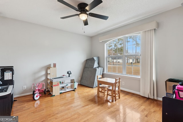 recreation room with ceiling fan, light hardwood / wood-style flooring, and a textured ceiling