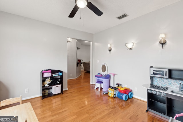 playroom with wood-type flooring and ceiling fan