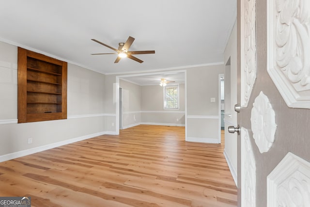 spare room with ceiling fan, crown molding, light hardwood / wood-style floors, and built in shelves