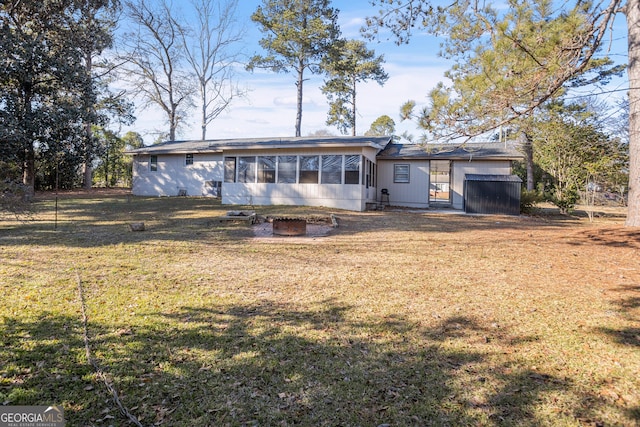 back of property with a yard and a fire pit