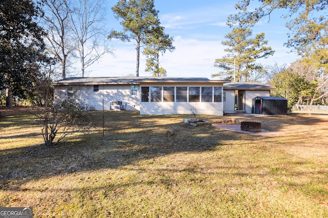 view of front of property featuring a storage shed, a front lawn, and a fire pit