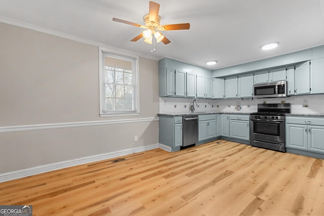 kitchen featuring sink, gray cabinets, stainless steel appliances, ornamental molding, and light hardwood / wood-style floors