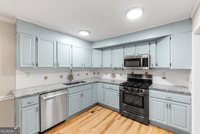 kitchen with sink, crown molding, light hardwood / wood-style flooring, stainless steel appliances, and light stone countertops