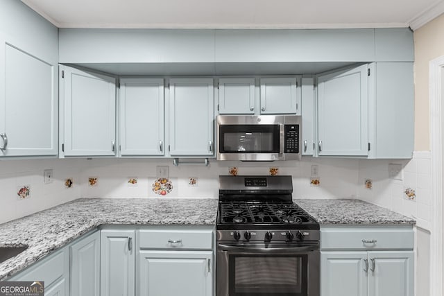 kitchen with crown molding, white cabinetry, appliances with stainless steel finishes, light stone countertops, and backsplash