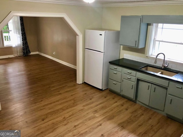 kitchen featuring sink, ornamental molding, white fridge, green cabinetry, and dark wood-type flooring