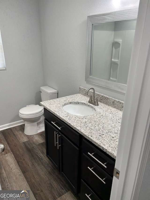 bathroom featuring wood-type flooring, vanity, and toilet