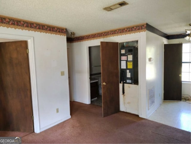 empty room with carpet floors, visible vents, a textured ceiling, and heating unit