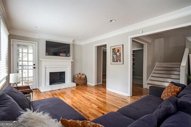 1574 Mayflower St, Atlanta, GA 30311 - living room with baseboards, light wood-style floors, a fireplace with raised hearth, stairs, and crown molding