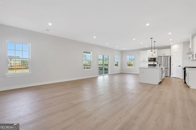 unfurnished living room featuring sink and light hardwood / wood-style floors