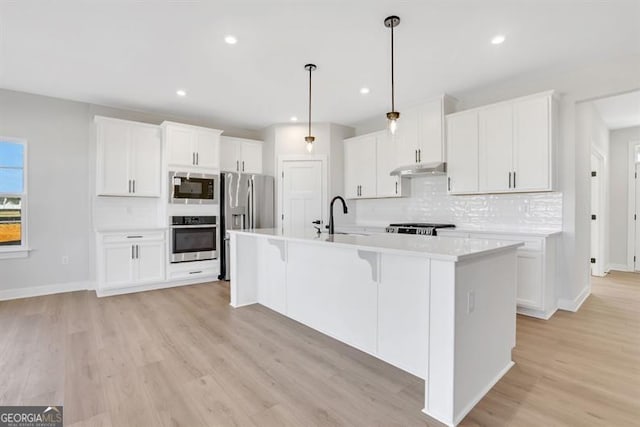 kitchen featuring hanging light fixtures, white cabinetry, a kitchen island with sink, and sink