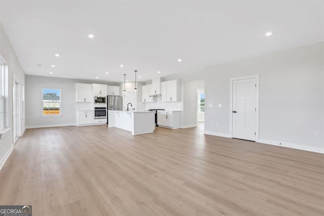 unfurnished living room featuring sink and light hardwood / wood-style flooring