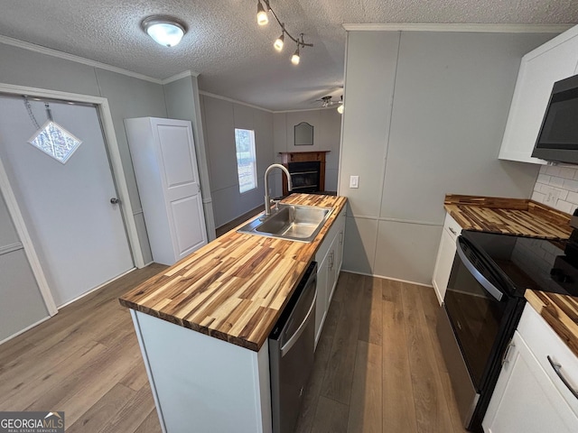 kitchen featuring sink, appliances with stainless steel finishes, butcher block counters, white cabinetry, and ornamental molding