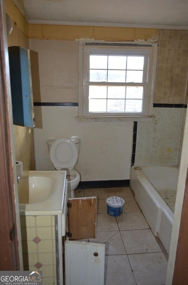 bathroom featuring a tub to relax in, vanity, toilet, crown molding, and tile patterned floors