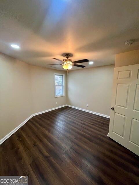 unfurnished room featuring dark wood-type flooring and ceiling fan