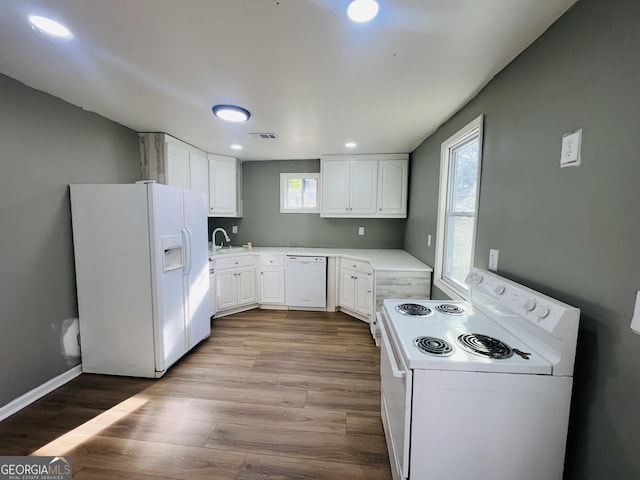 kitchen with white cabinetry, white appliances, a healthy amount of sunlight, and light hardwood / wood-style flooring