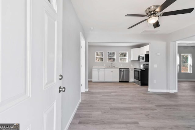 unfurnished living room featuring sink, light hardwood / wood-style floors, and ceiling fan