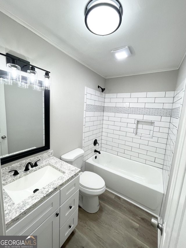 full bathroom featuring wood-type flooring, tiled shower / bath combo, ornamental molding, vanity, and toilet