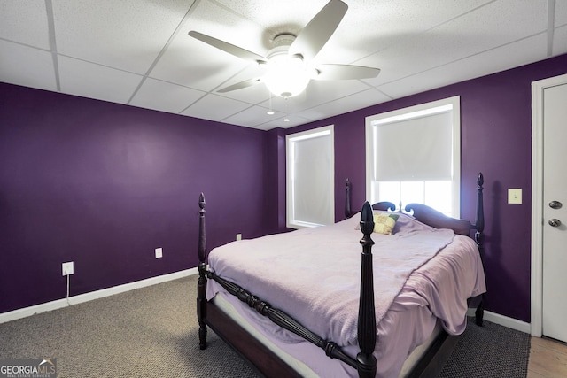 carpeted bedroom with ceiling fan and a drop ceiling