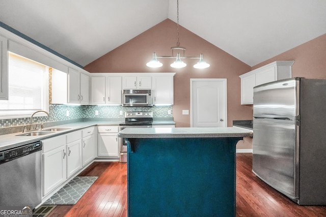 kitchen featuring lofted ceiling, sink, stainless steel appliances, a center island, and decorative light fixtures