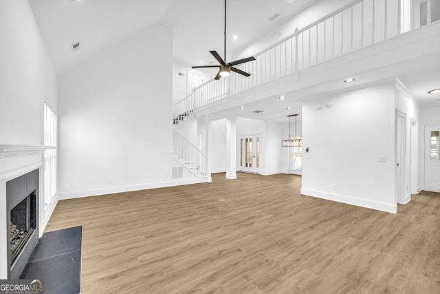 unfurnished living room featuring crown molding, hardwood / wood-style floors, a towering ceiling, and ceiling fan