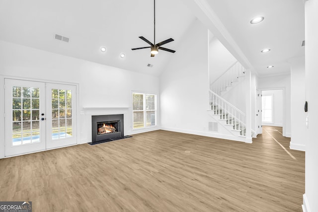 unfurnished living room with french doors, ceiling fan, light hardwood / wood-style floors, and high vaulted ceiling