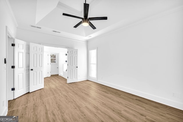 unfurnished bedroom featuring light hardwood / wood-style flooring, ornamental molding, a raised ceiling, and ceiling fan