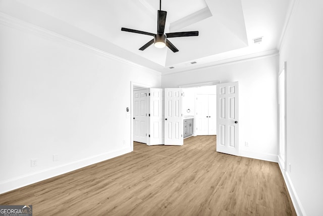 unfurnished bedroom featuring light hardwood / wood-style flooring, ornamental molding, a raised ceiling, and ceiling fan