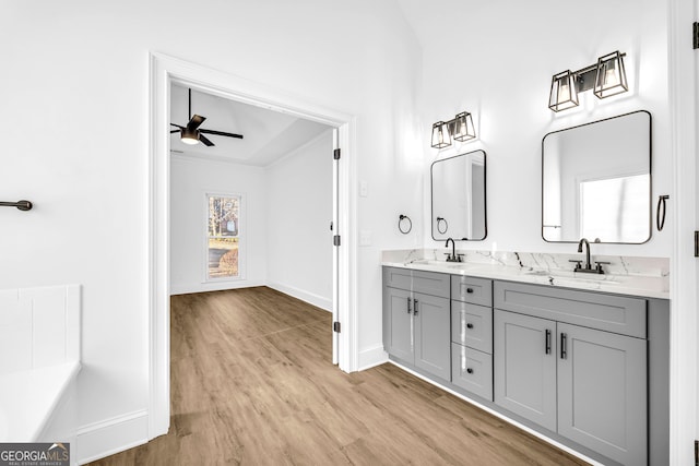 bathroom featuring wood-type flooring, ornamental molding, vanity, and ceiling fan