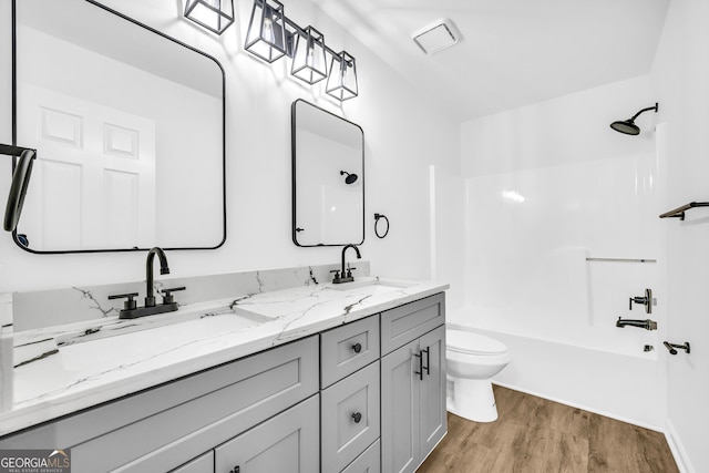 full bathroom with vanity, hardwood / wood-style floors, shower / bathtub combination, and toilet