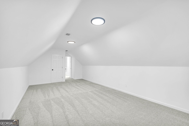 bonus room with light colored carpet and vaulted ceiling