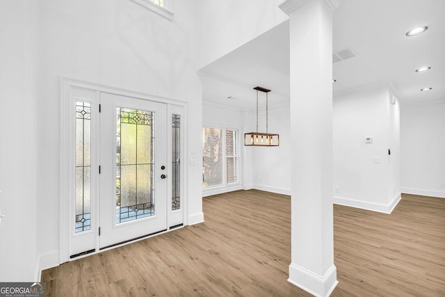 entryway featuring decorative columns, crown molding, and light hardwood / wood-style flooring