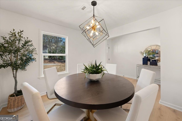 dining space with a notable chandelier and light hardwood / wood-style floors