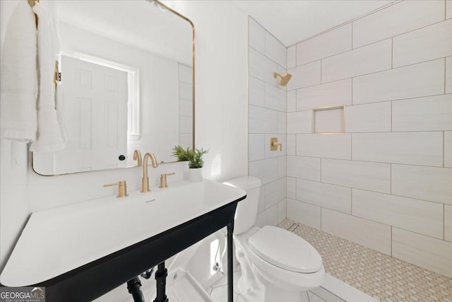 bathroom with vanity, toilet, and tiled shower